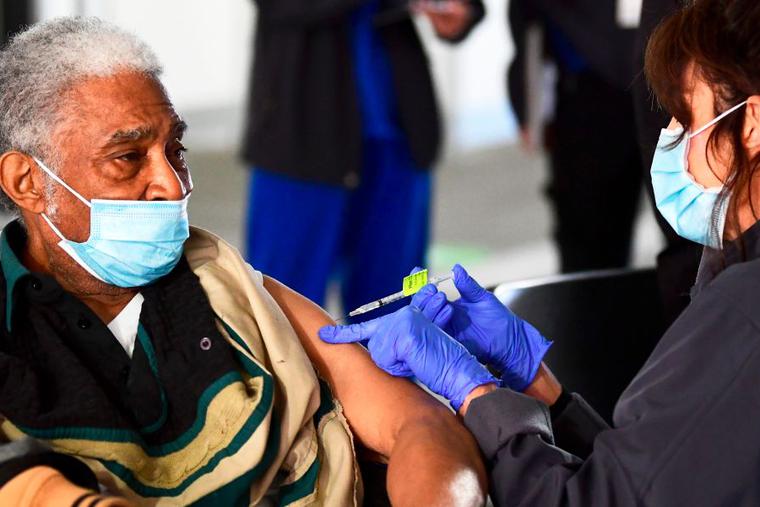 Elton Jackson, 80, looks on as he receives his COVID-19 vaccine, administered by Kathryne Acuna, director of Ambulatory Clinical Services at Kaiser Permanente, on Feb. 5, the opening day of a large-scale vaccination site at a parking structure at Cal Poly Pomona University in Pomona, California. The elderly are among those given priority during the vaccine rollout across the country.