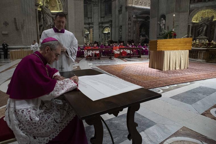 The late Benedict XVI’s personal secretary, Archbishop Georg Gänswein, signs an official document after the casket of the former pope was closed during a private ceremony on Jan. 4 in St. Peter's Basilica.