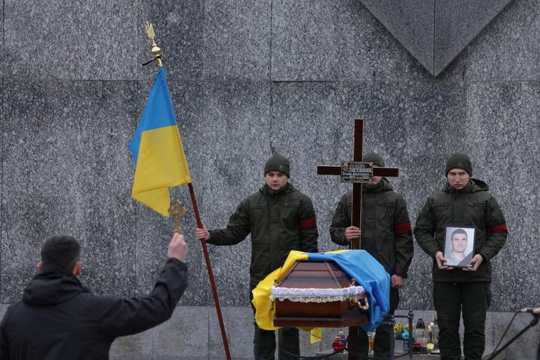A priest holds a cross towards the coffin of Ruslan Zastavny, 33, a volunteer in Ukraine's Territorial Defence Forces, during his funeral at the Field of Mars cemetery on Feb. 20, 2023 in Lviv, Ukraine. Feb. 24 marked the first anniversary of Russia's ongoing war in Ukraine.  