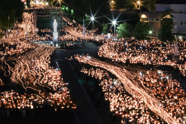 Pilgrims process by candlelight before the Sanctuary of Our Lady of Lourdes in France.