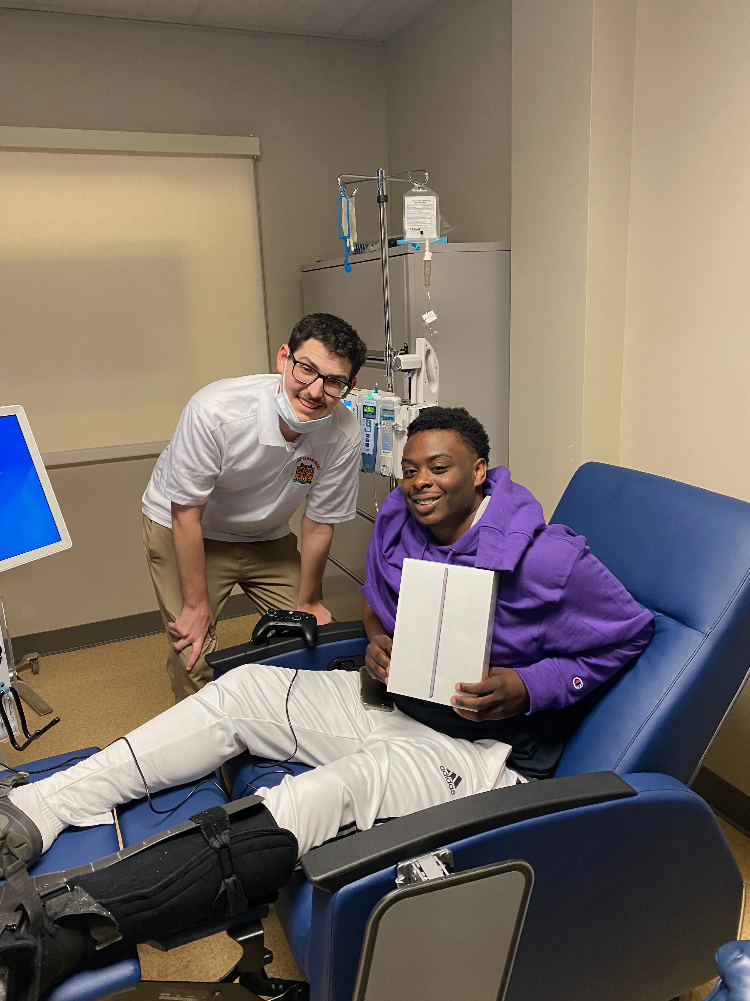 Bryce Newman poses with a young patient receiving an iPad. The Miracle at Manchester Foundation