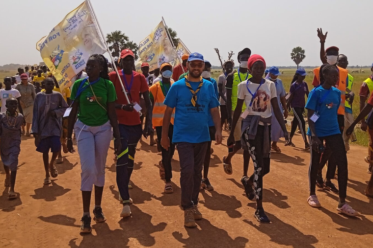 Bishop Christian Carlassare (center) walks with youth on the nine-day pilgrimage wearing a scarf that belongs to scouts from his hometown in Italy.